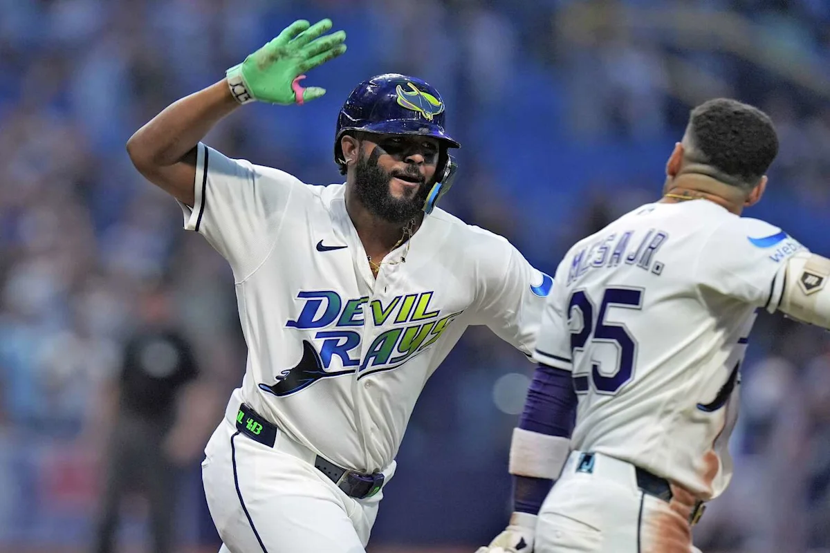 Two Tampa Bay Rays players in white uniforms celebrate on the field during a game.