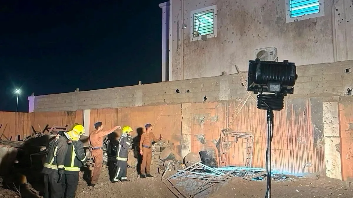 Emergency responders inspect debris beside a damaged building at night.