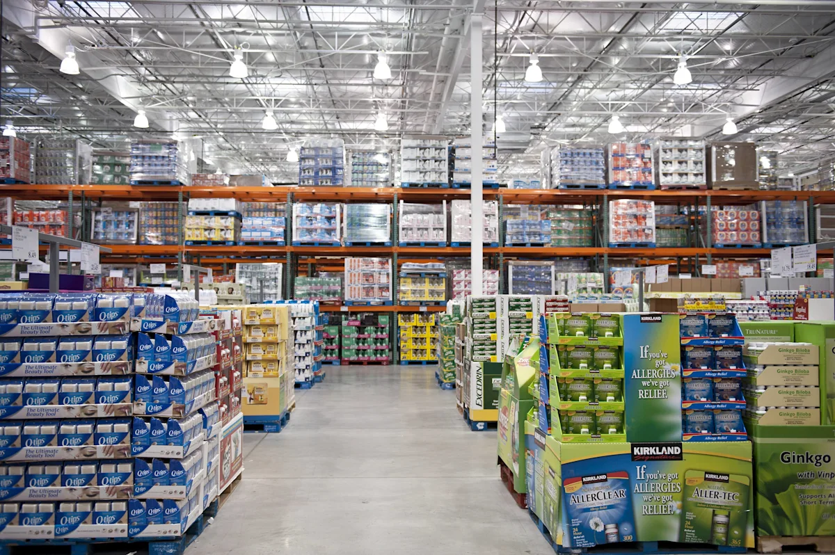 Warehouse store aisle displaying stacked Kirkland allergy medicine and other bulk products on pallets