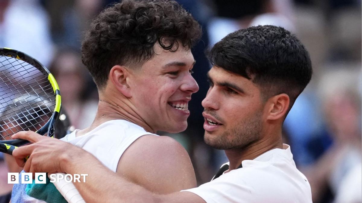 Two tennis players embrace near the net, with a racket visible beside them.