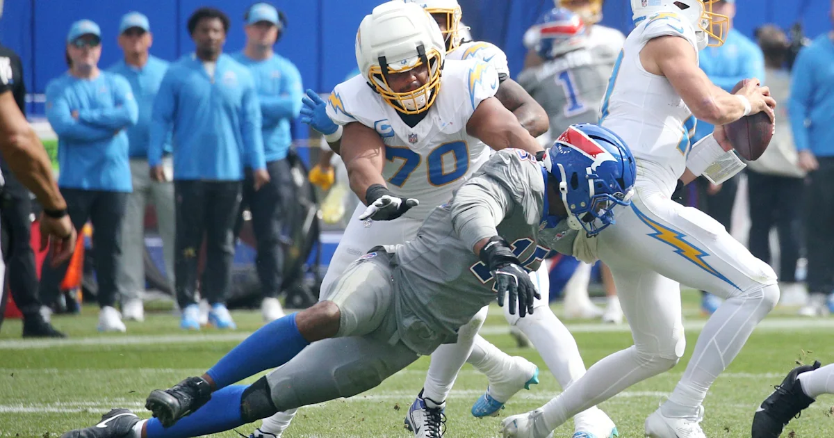 A Chargers lineman reaches toward a Bills defender tackling a quarterback during a football game.