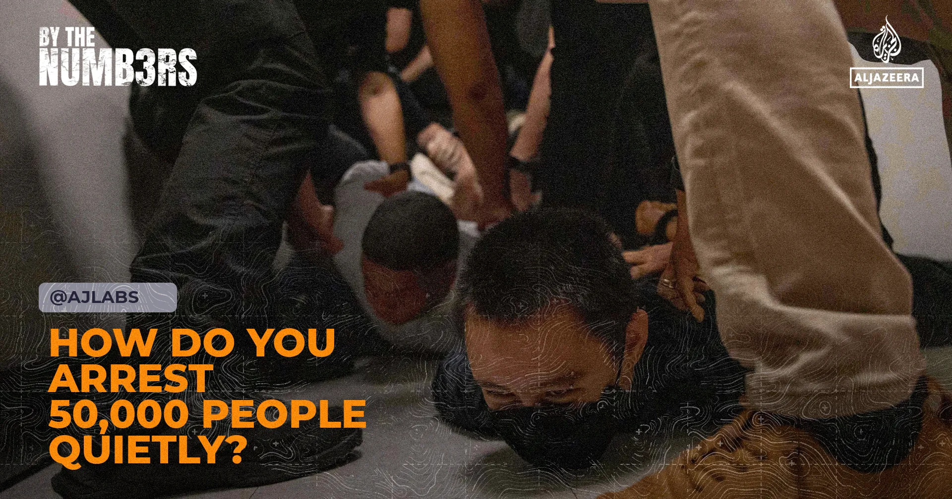 Several people restrain a person face-down on the floor during an apparent arrest.