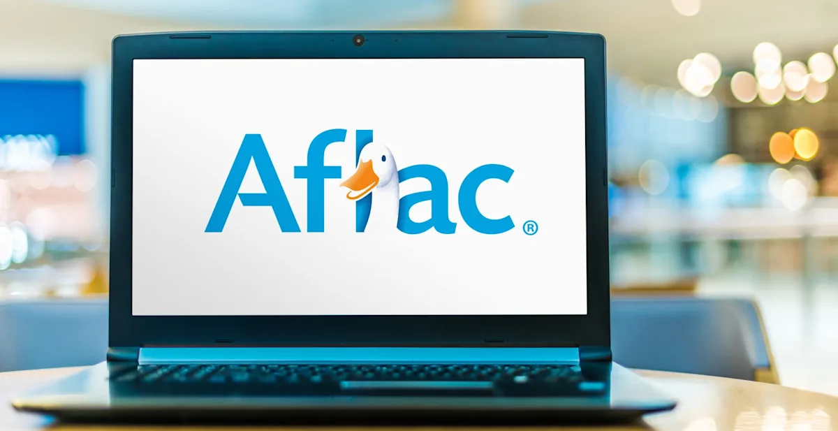 Laptop displaying the Aflac logo on a white screen in a softly blurred indoor setting.
