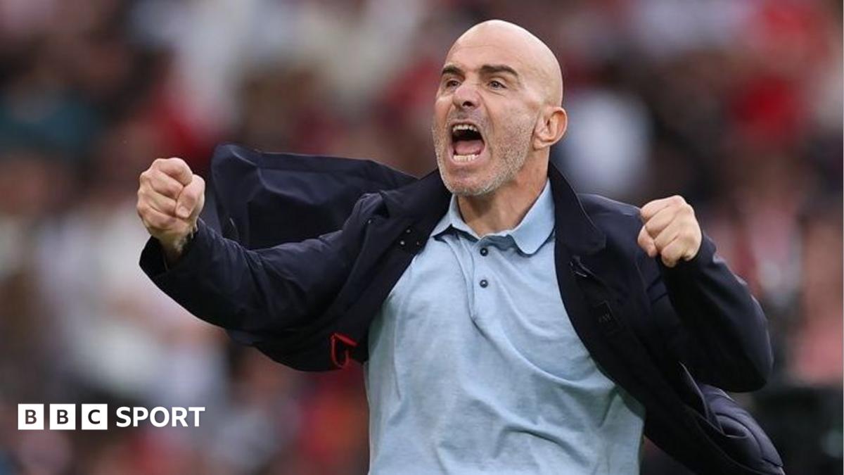 Bald football manager shouting with clenched fists while pulling open his dark jacket.