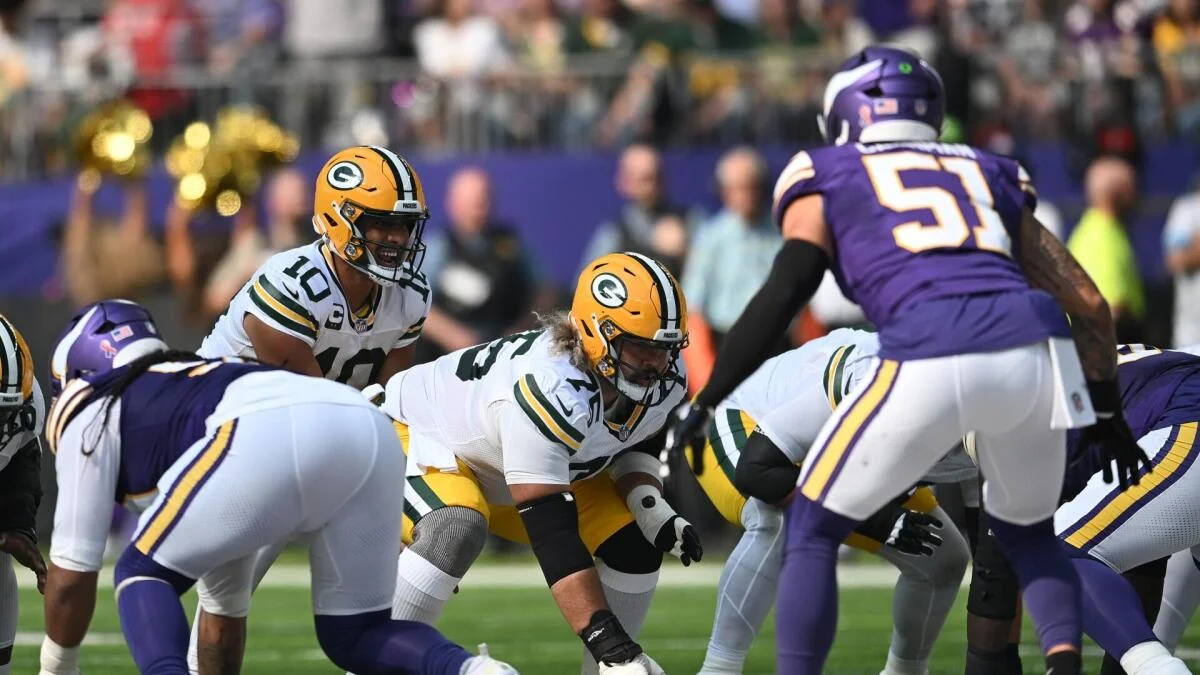 Green Bay Packers line up under center against Minnesota Vikings defenders before a snap.