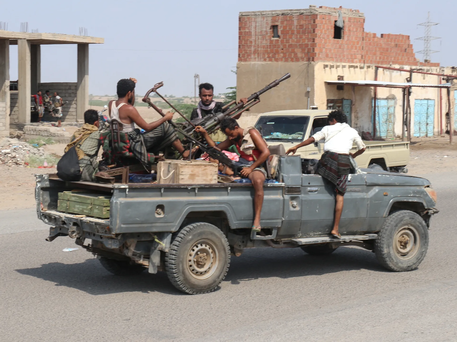 Armed men riding in a pickup truck carrying a mounted weapon through an urban area