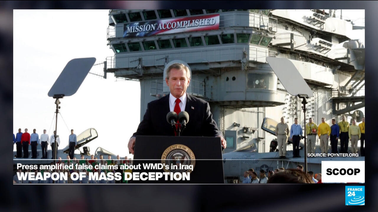 Former U.S. president speaking at a podium aboard a naval ship, with crew members behind him