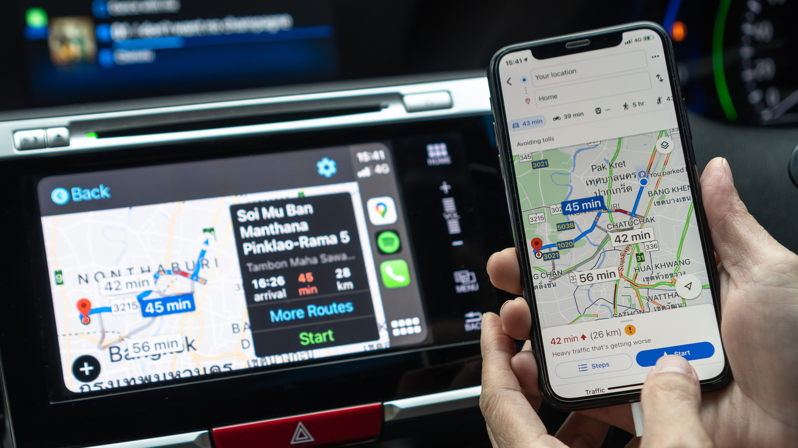 A hand holds a phone displaying Google Maps beside a car dashboard navigation screen.