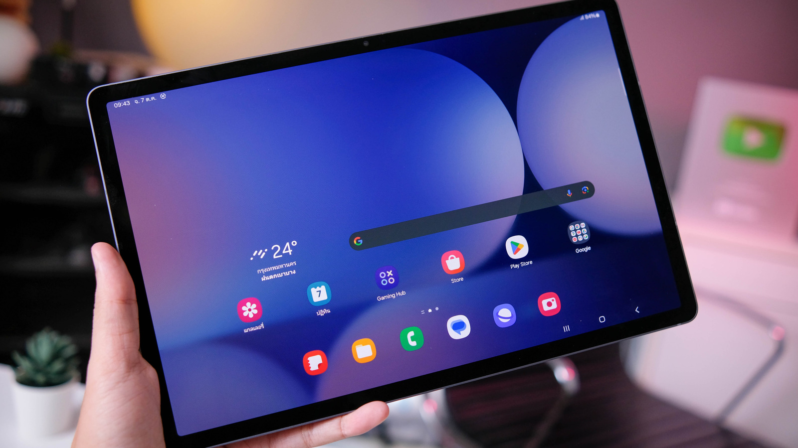 Hand holding a Samsung Galaxy tablet displaying its colorful home screen