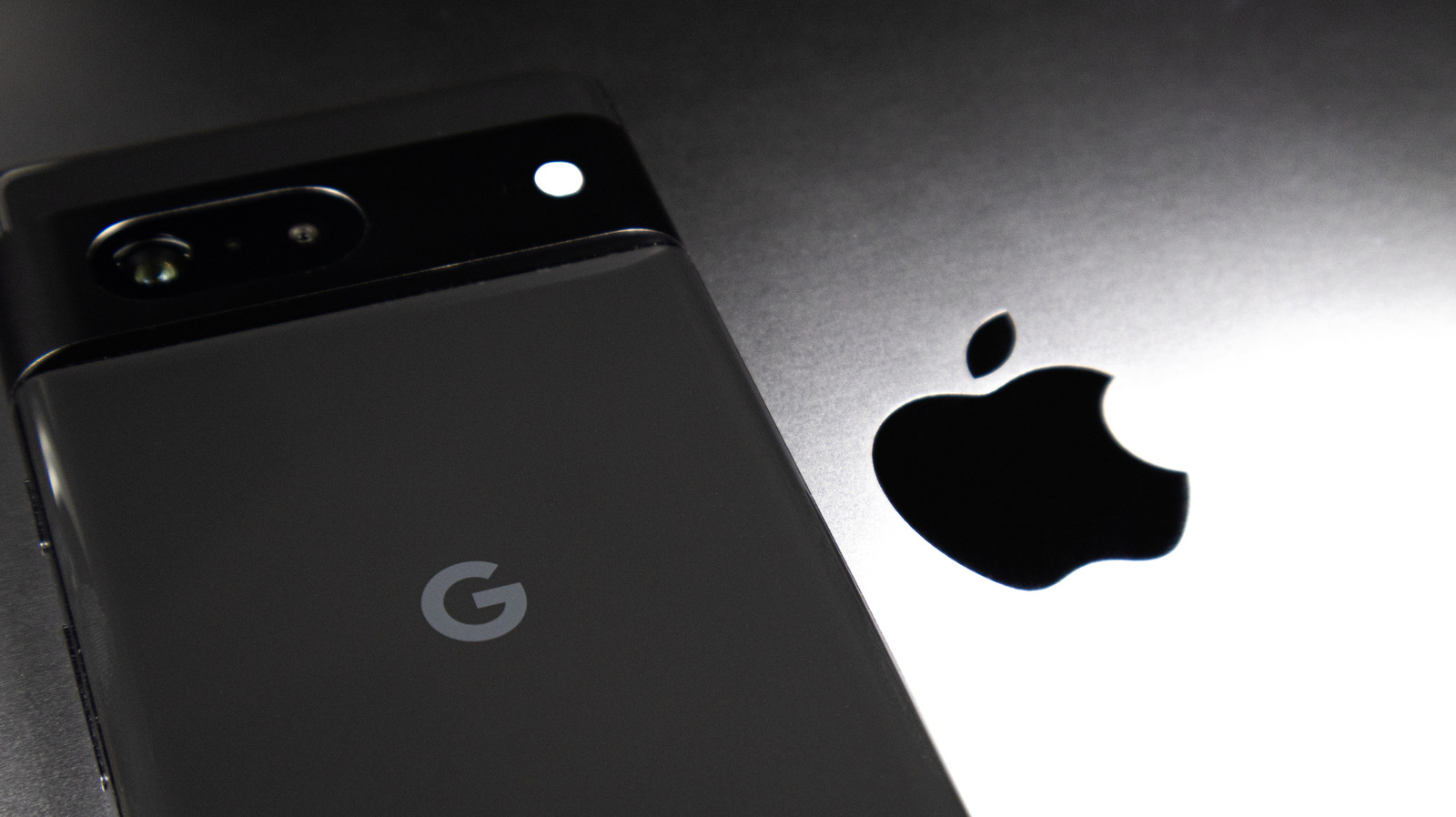 Black Google smartphone beside a white Apple laptop displaying the Apple logo