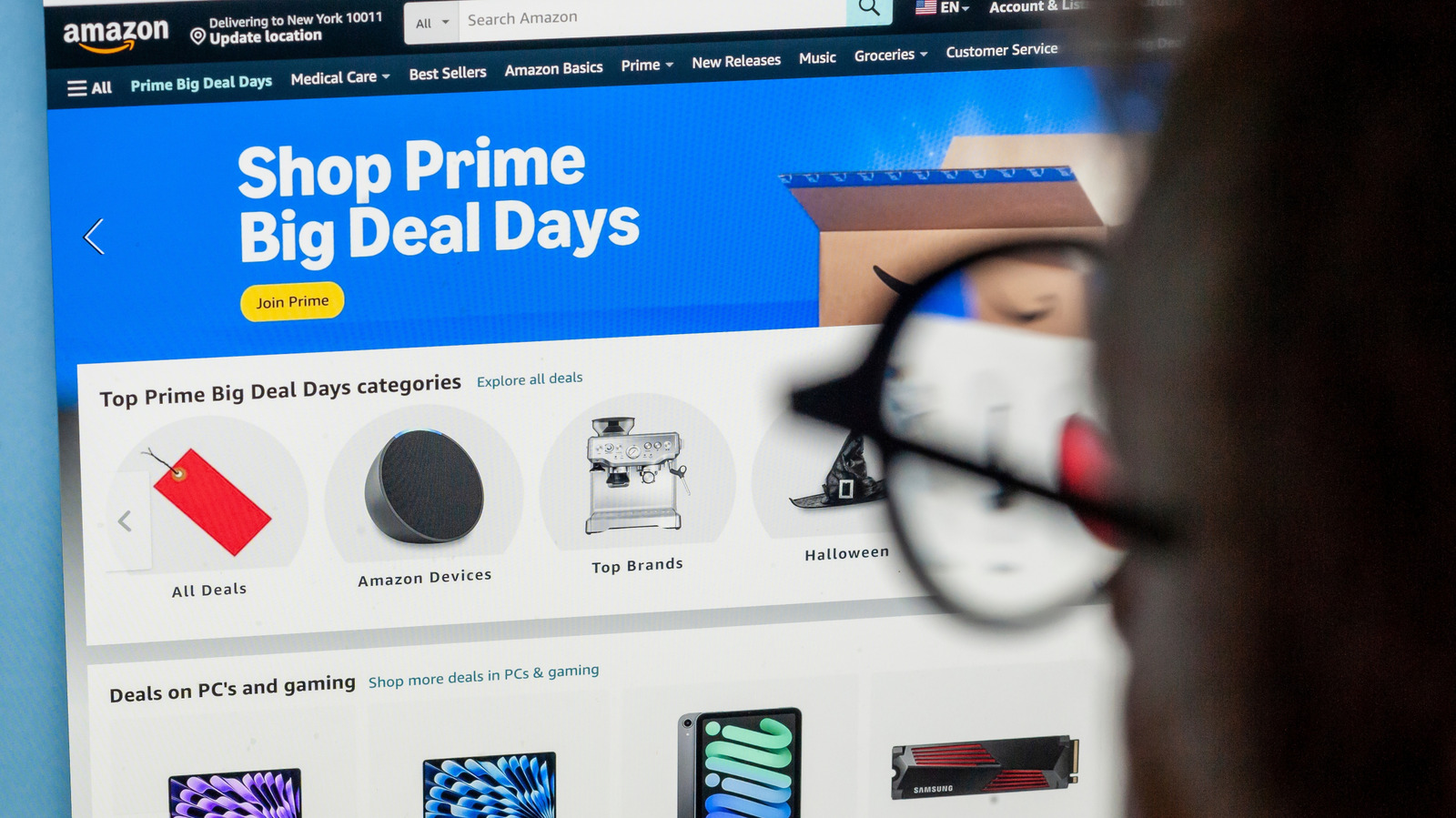 Amazon Prime Big Deal Days webpage displayed on a screen, partially obscured by a blurred shopping cart handle.