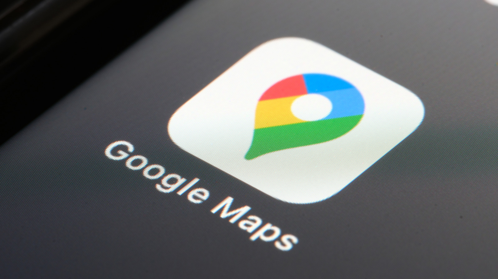 Close-up of Google Maps logo displayed on a dark screen with visible pixel texture