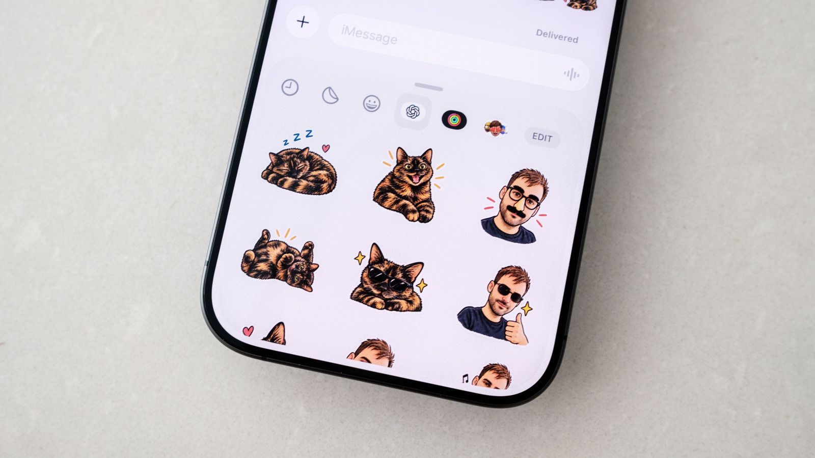 Close-up of a smartphone displaying cat and person stickers in a messaging app.