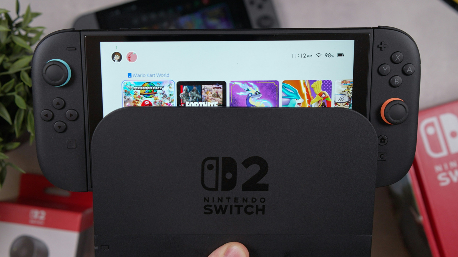 Nintendo Switch 2 console displaying a game selection screen while held in front of its dock