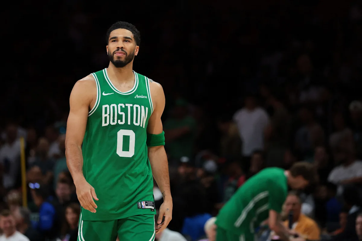 Boston Celtics player Jayson Tatum stands on a basketball court in a green No. 0 jersey.