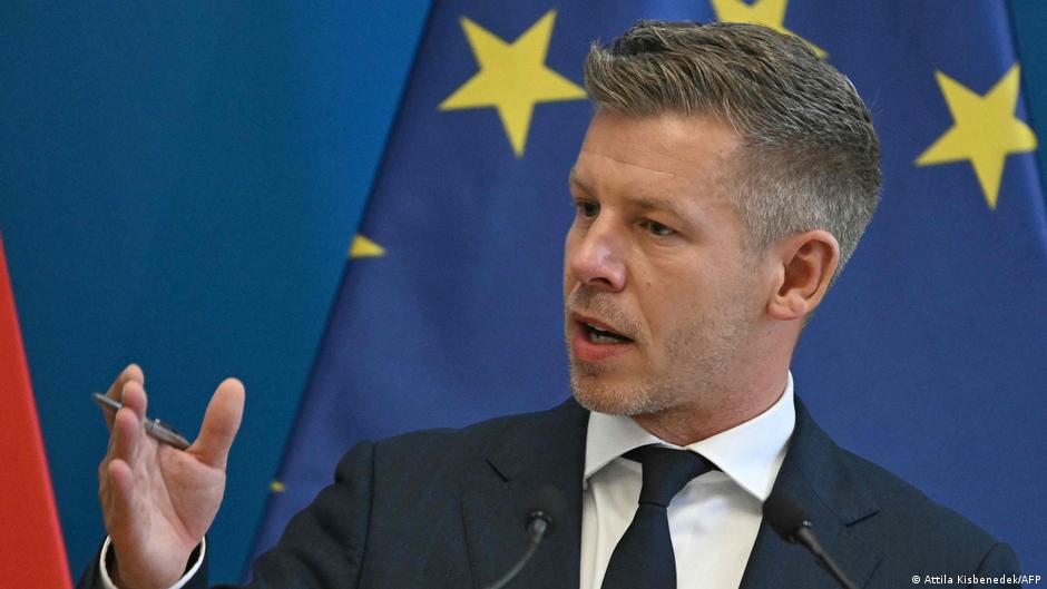 Suited man speaking at a podium with European Union flags behind him