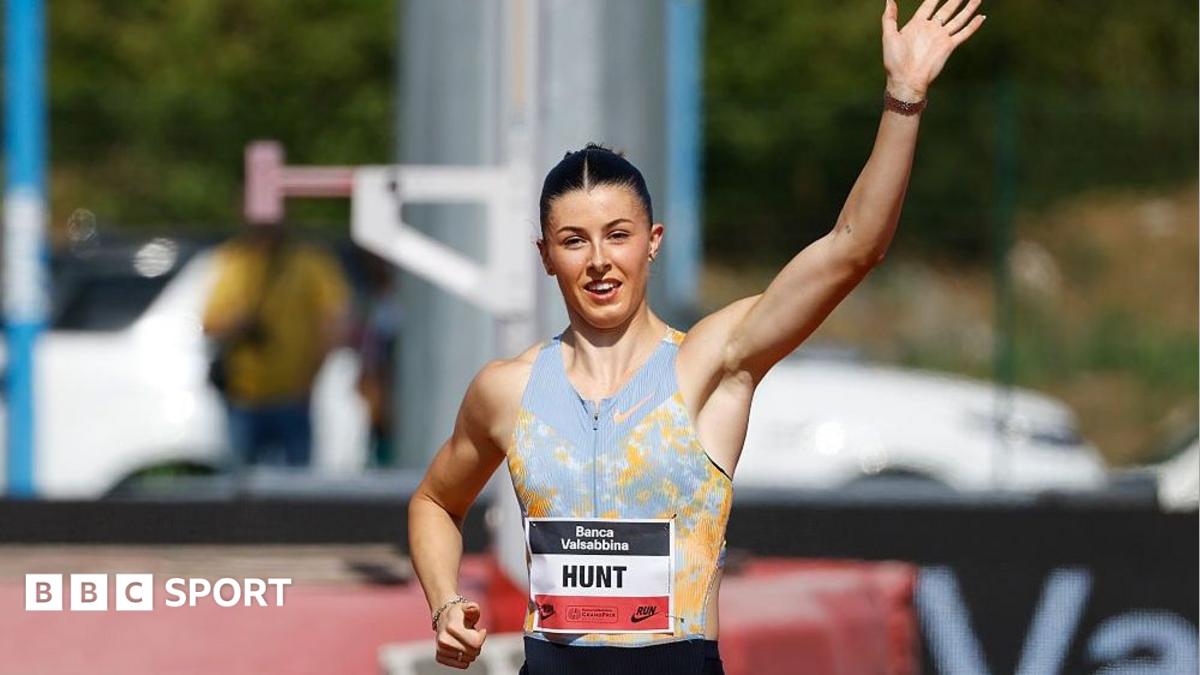 Female athlete raises one arm while running on a track, wearing a Hunt bib and BBC Sport branding.