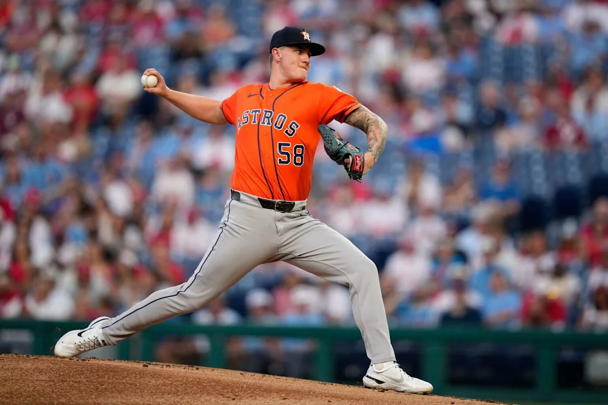 Astros pitcher in orange uniform delivers a baseball during a game.