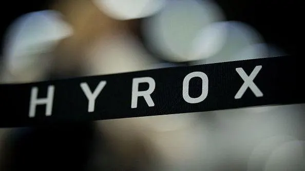 Close-up of HYROX lettering on a black strip against a blurred background