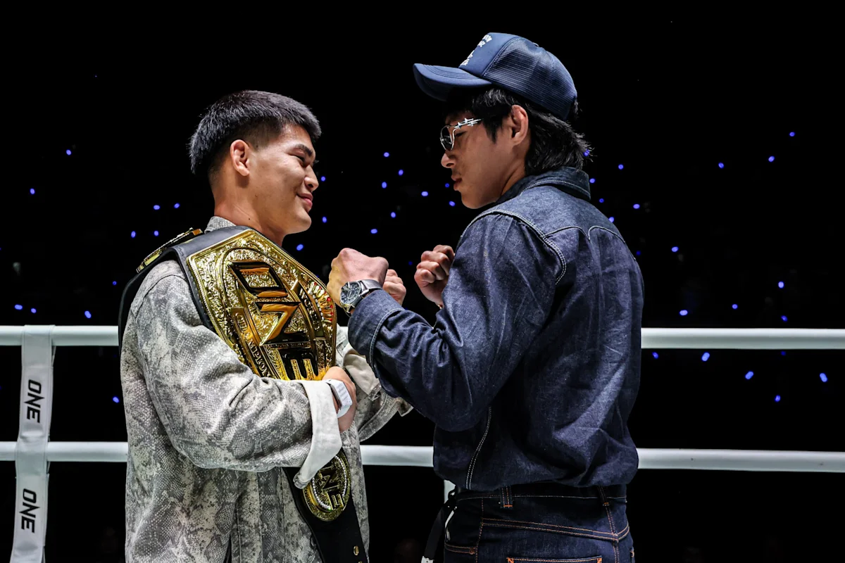 Two fighters face each other in a ring, one wearing a championship belt.