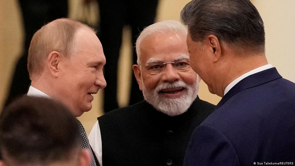 Vladimir Putin, Narendra Modi and Xi Jinping converse at a formal gathering.