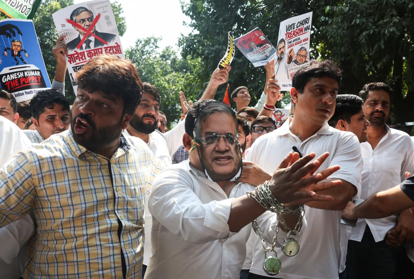 Protesters carry political placards as a man in handcuffs gestures in front of the crowd.
