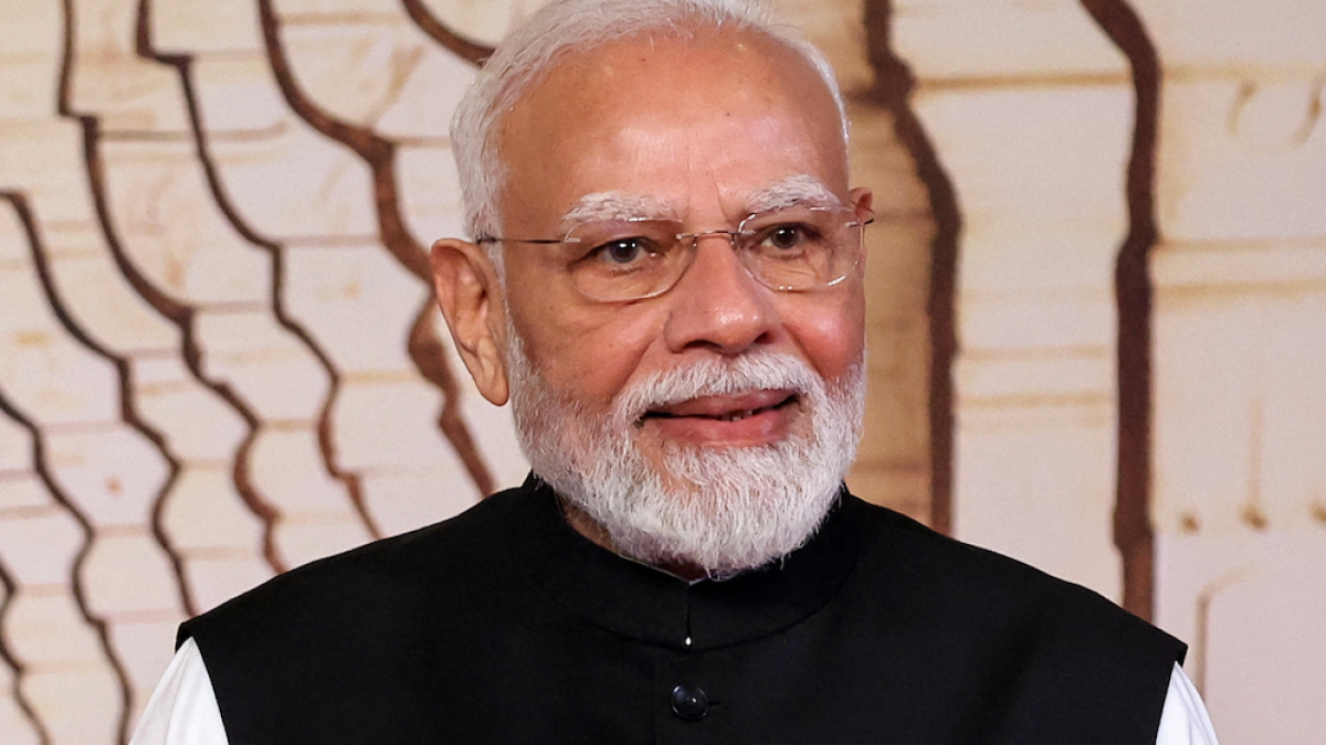 Indian man with white hair and beard wearing glasses and a black vest, facing the camera