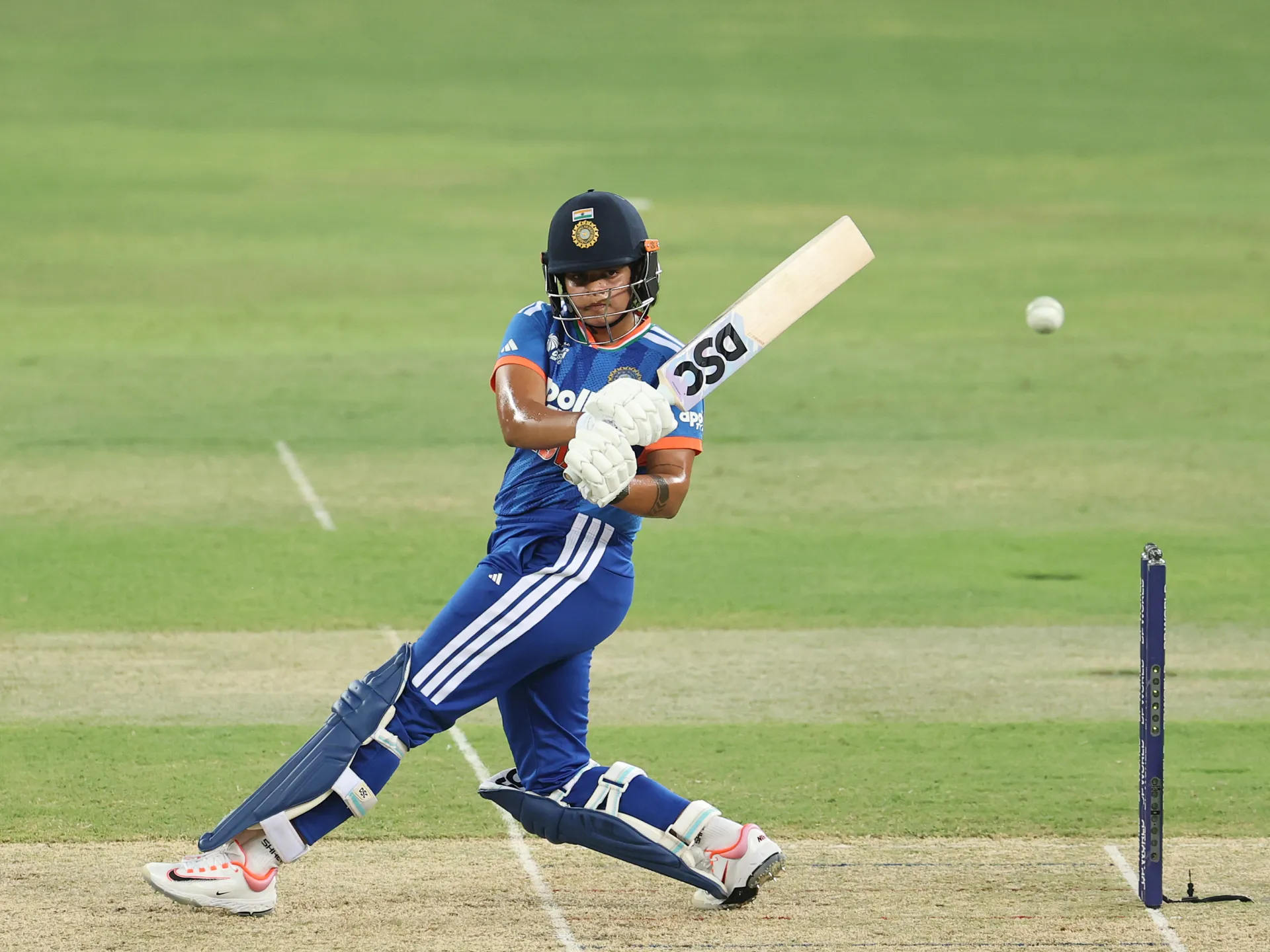 Cricketer in blue India kit plays a shot with bat during a match