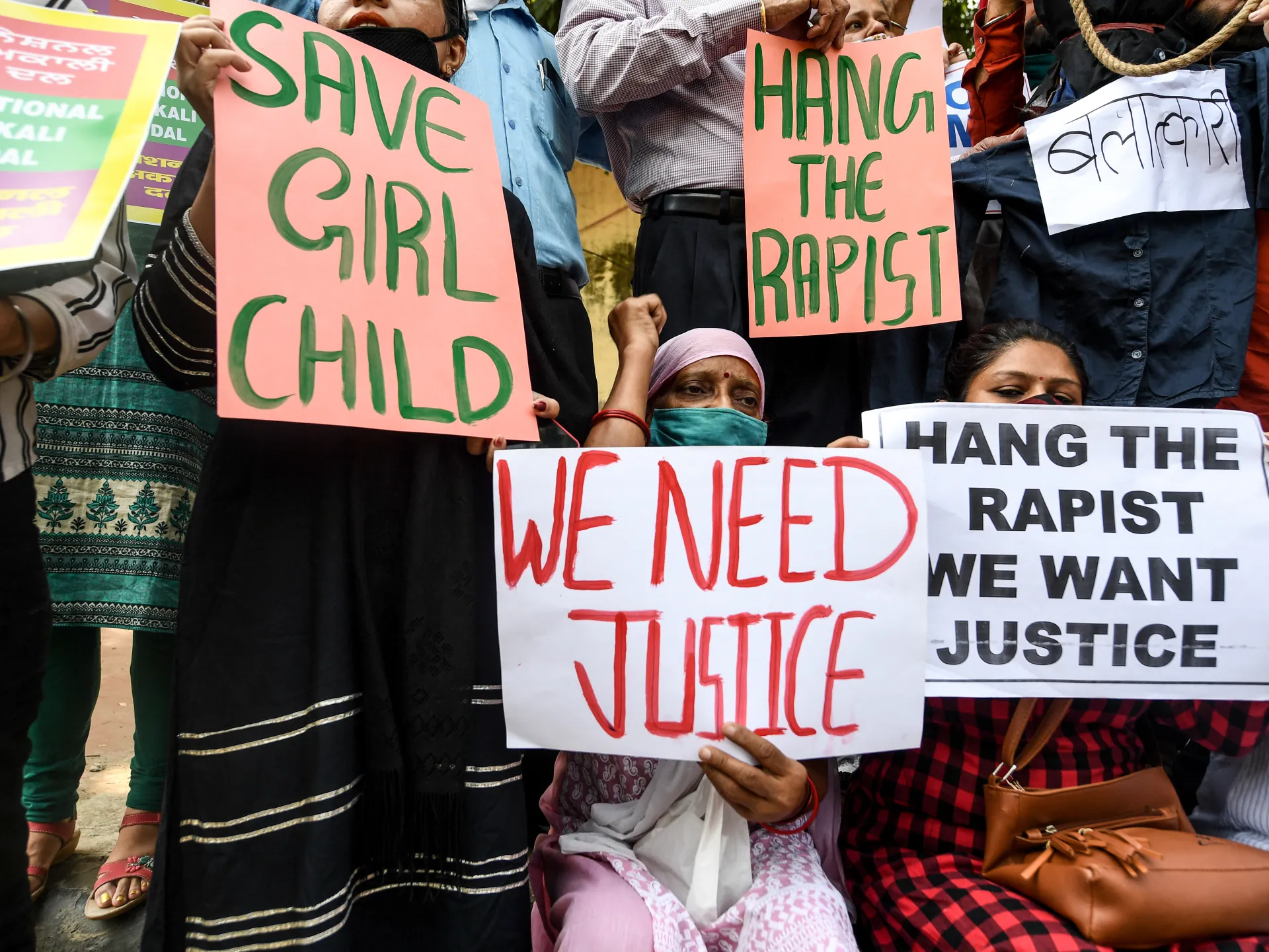Protesters hold signs reading “Save Girl Child,” “Hang the Rapist,” and “We Need Justice.”