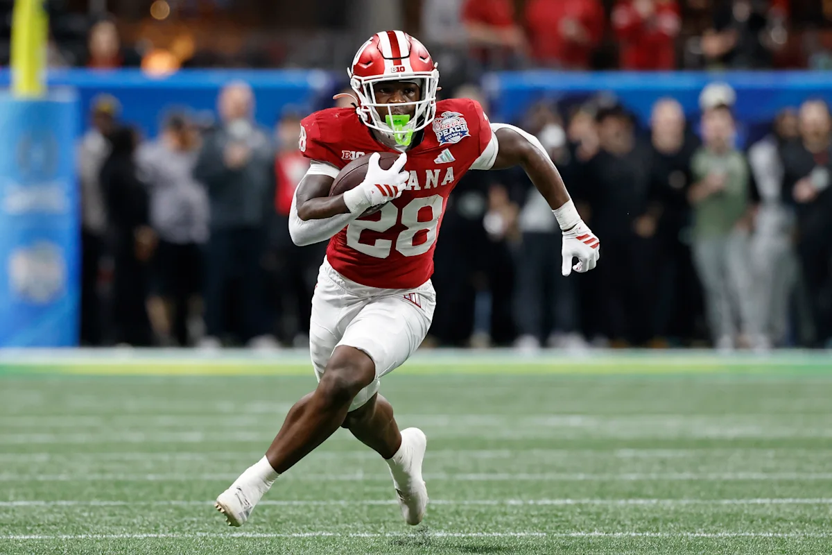 Indiana football player in red uniform runs with the ball during a game.