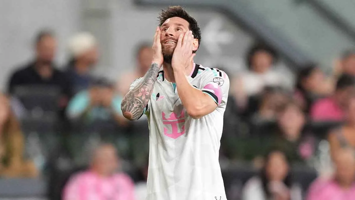 Lionel Messi in a white Inter Miami jersey holds his face during a match