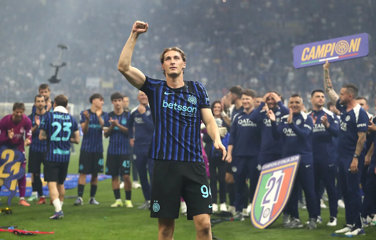 Young footballer in Inter Milan kit raises a fist during a trophy celebration with teammates