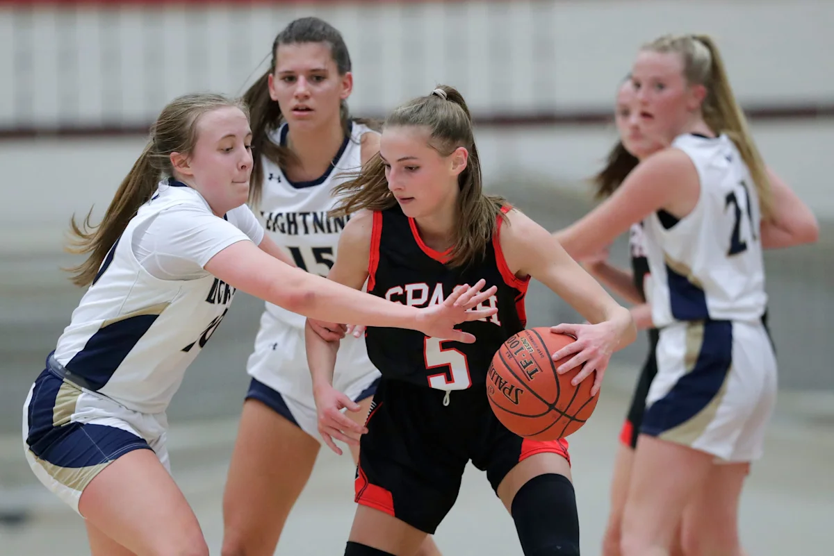 Youth basketball players compete for possession during a girls' game.