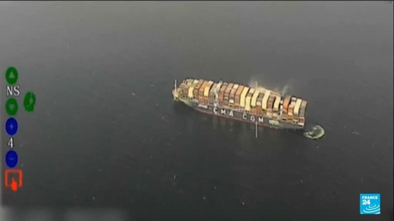 Aerial view of a container ship at sea with a small object nearby