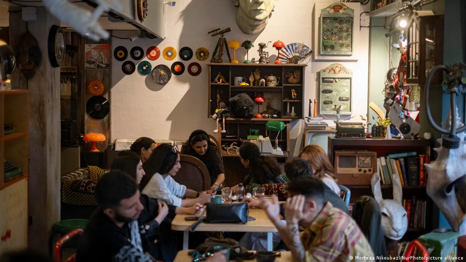 Crowded café with patrons seated at tables amid vintage decorations and antique furnishings