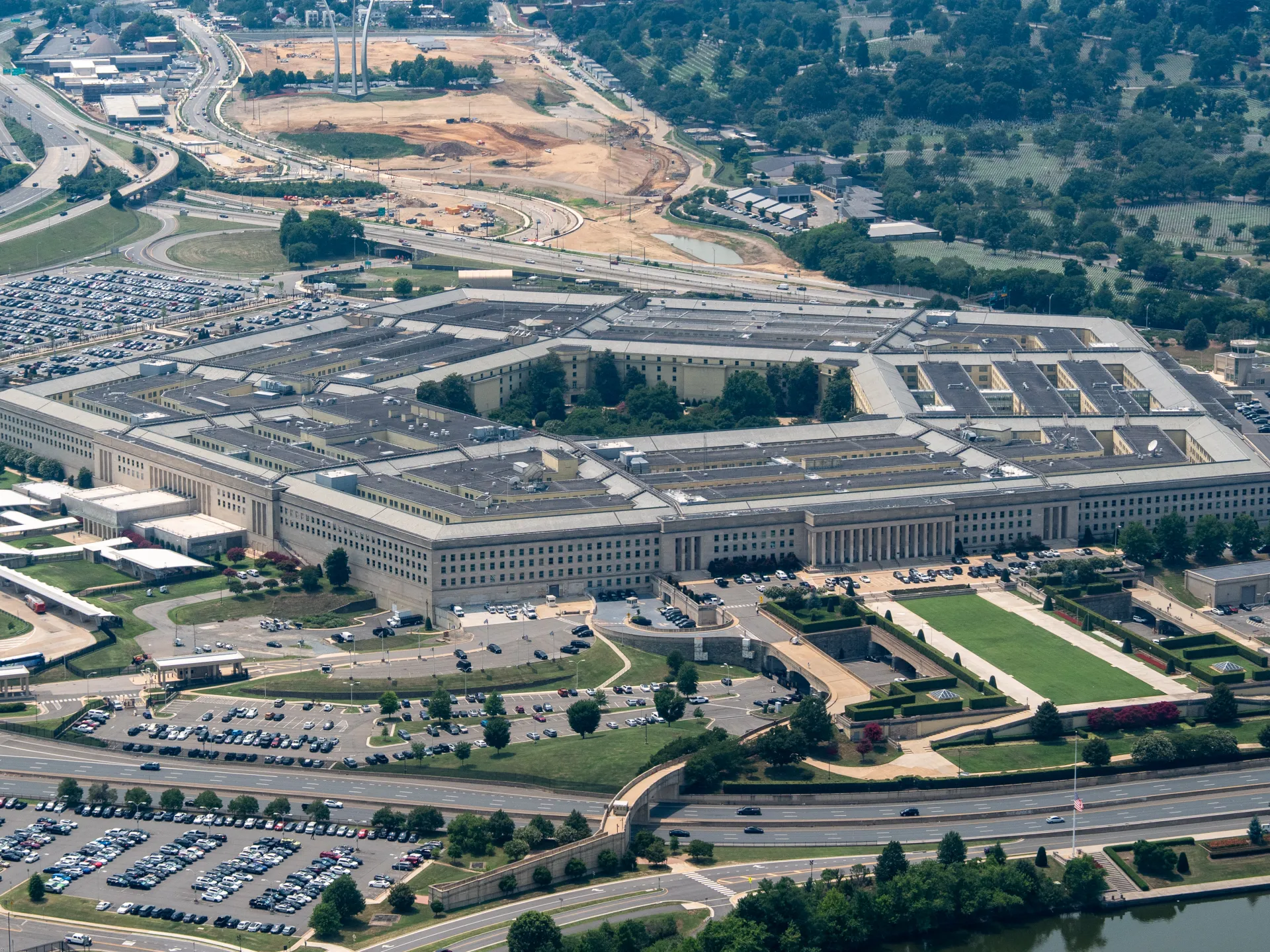 Aerial view of a sprawling government complex surrounded by highways, parking lots, trees, and construction.