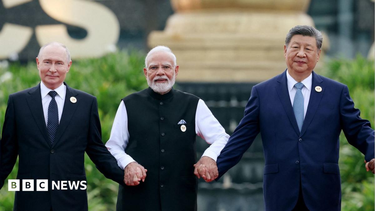Three suited political leaders stand outdoors, holding hands in a posed group photograph.