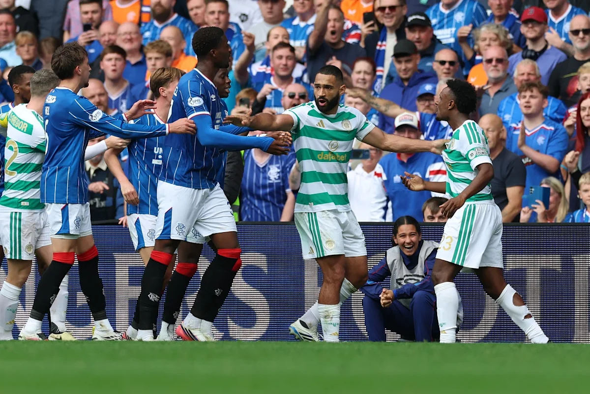 Celtic and Rangers players clash during a tense football match as fans watch from the stands.