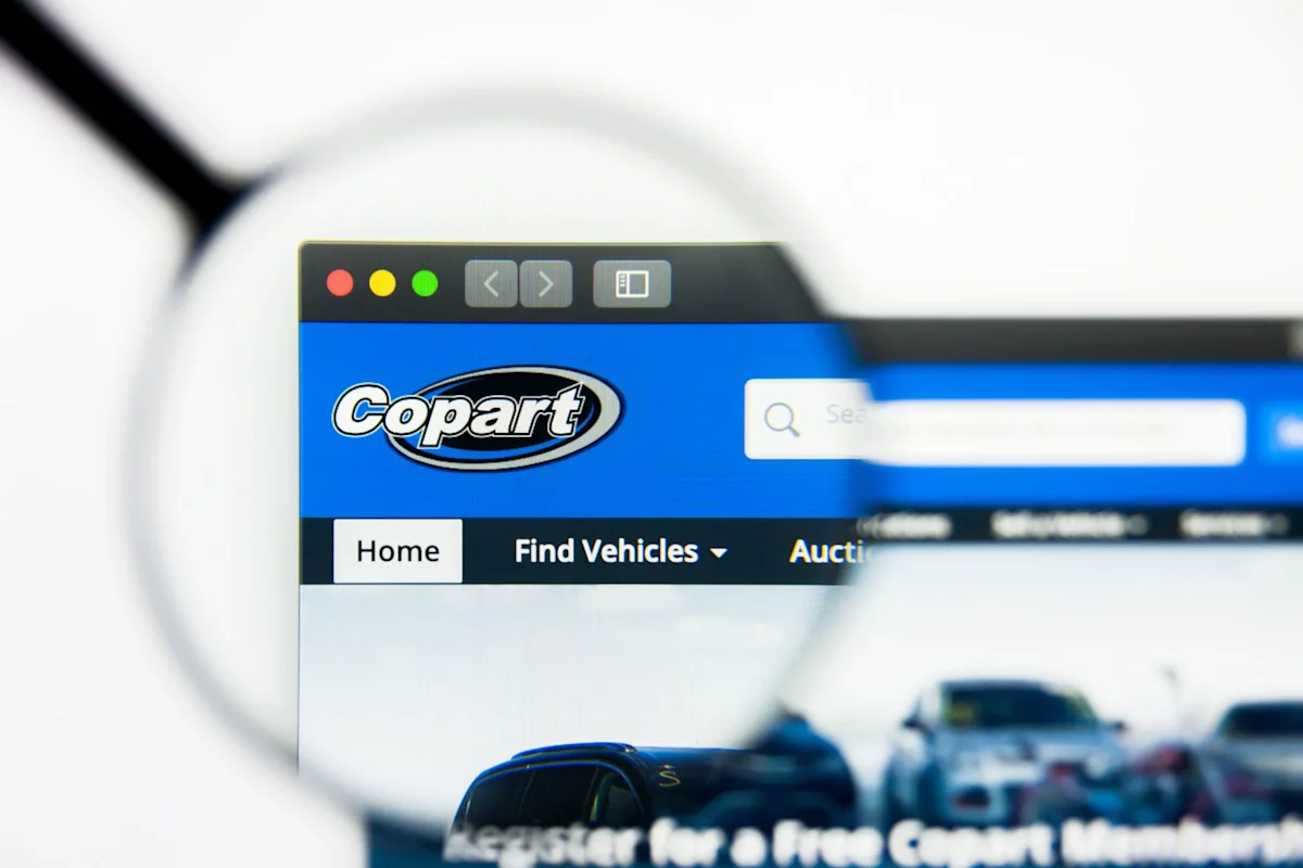 Magnifying glass over a computer screen displaying Copart's website and vehicle listings