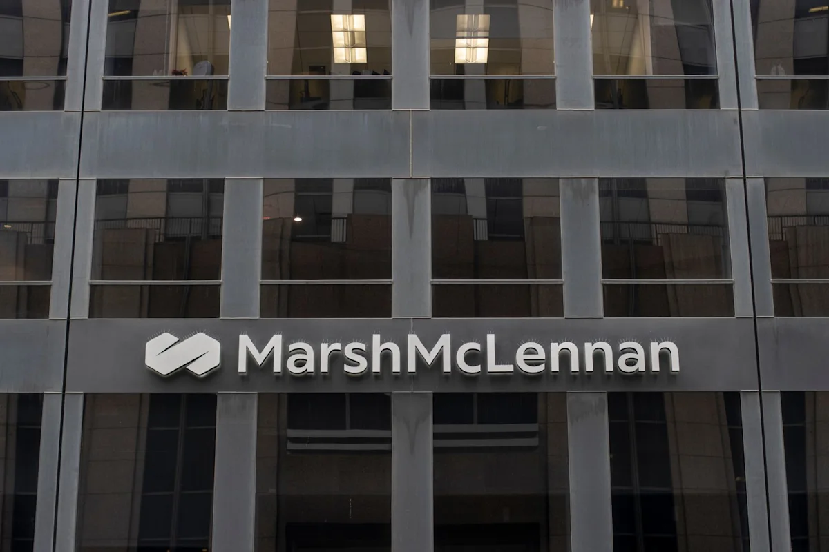 Marsh McLennan logo displayed on the exterior of a modern glass office building