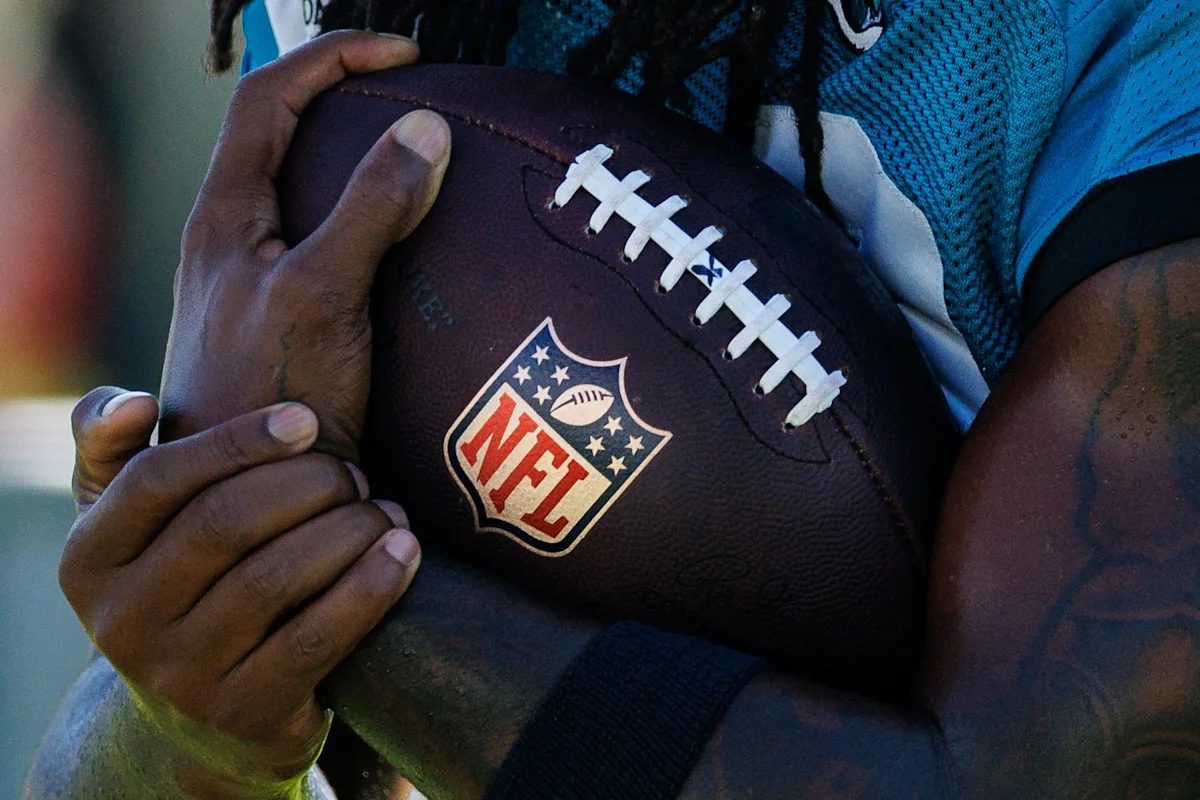 Close-up of a player holding a football while wearing a blue jersey.