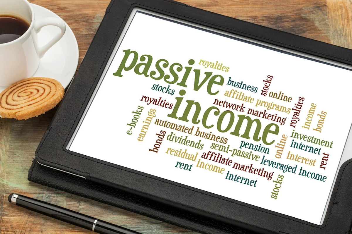 Tablet displaying colorful passive income concept beside coffee, cookie, pen, and wooden desk