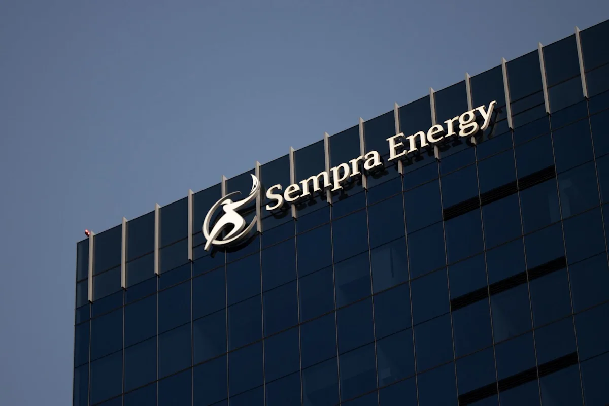 Sempra Energy logo displayed on the facade of a dark glass office building beneath a blue sky