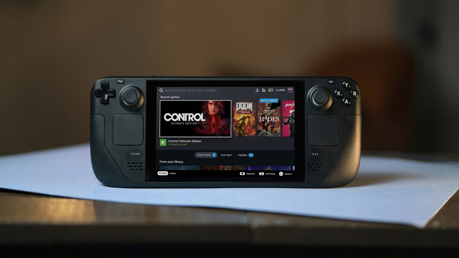 Steam Deck handheld gaming console displaying its game library on a tabletop