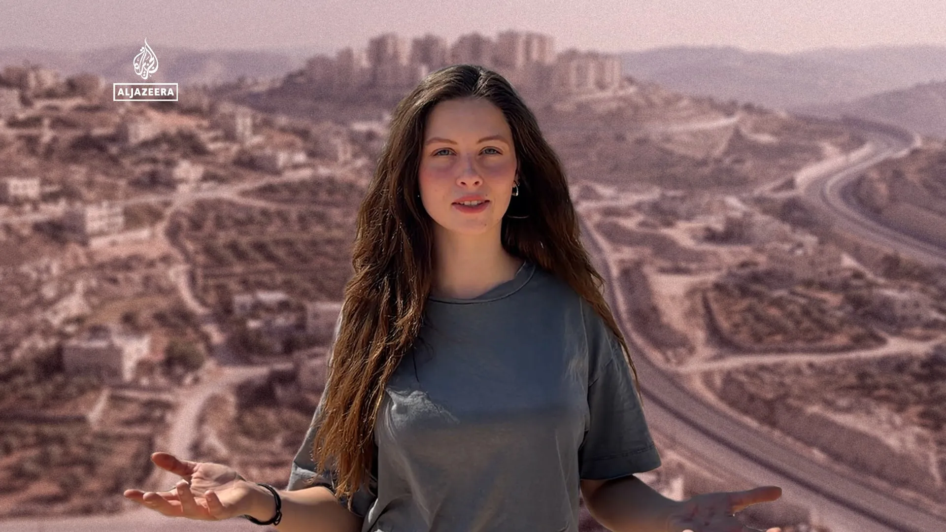 Woman gesturing in front of a blurred aerial view of a densely built urban area.
