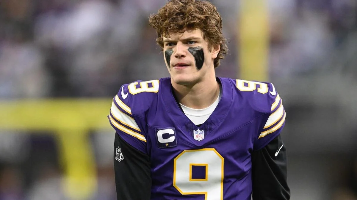 Football player in a purple number 9 jersey with black eye paint stands on the field.
