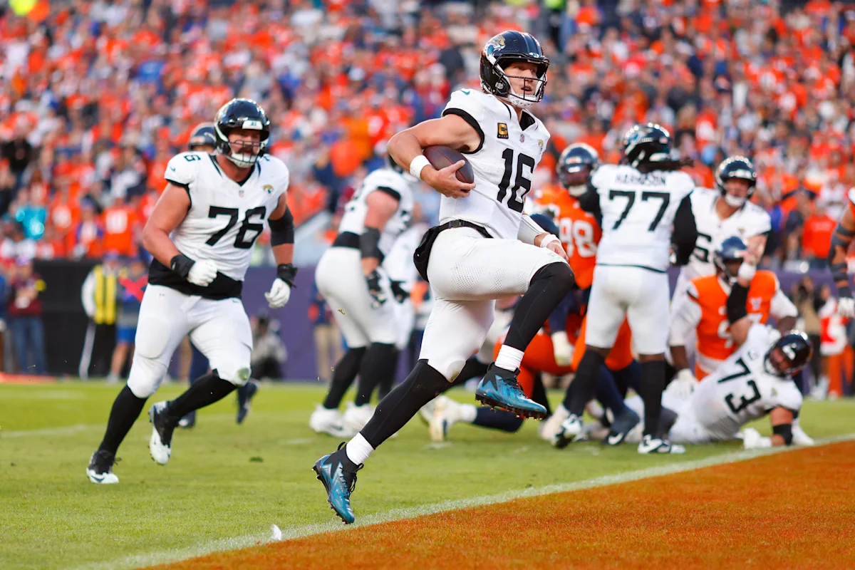 Jacksonville quarterback runs with the football as teammates block during a crowded football game.