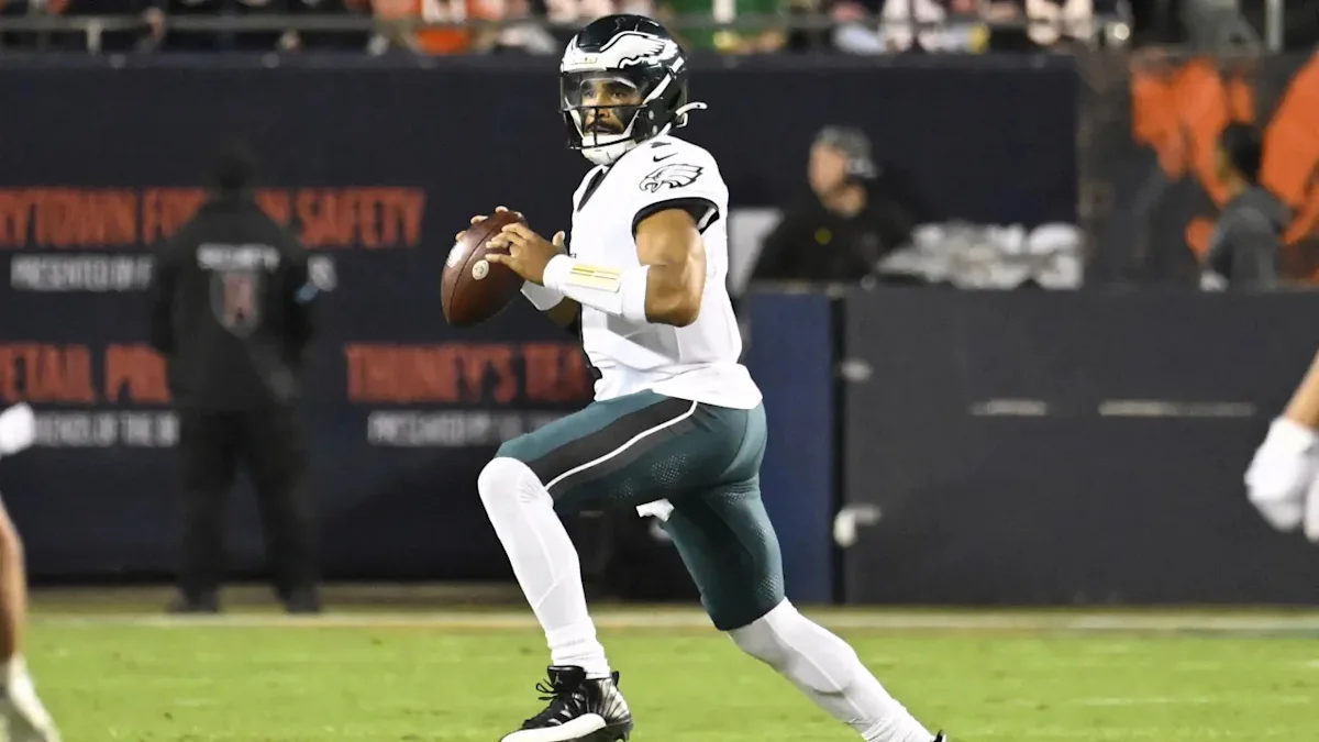 A football player in an Eagles uniform holds the ball while preparing to throw during a game.