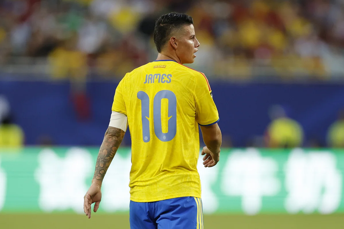 Footballer wearing Colombia's yellow No. 10 jersey walks across the pitch.