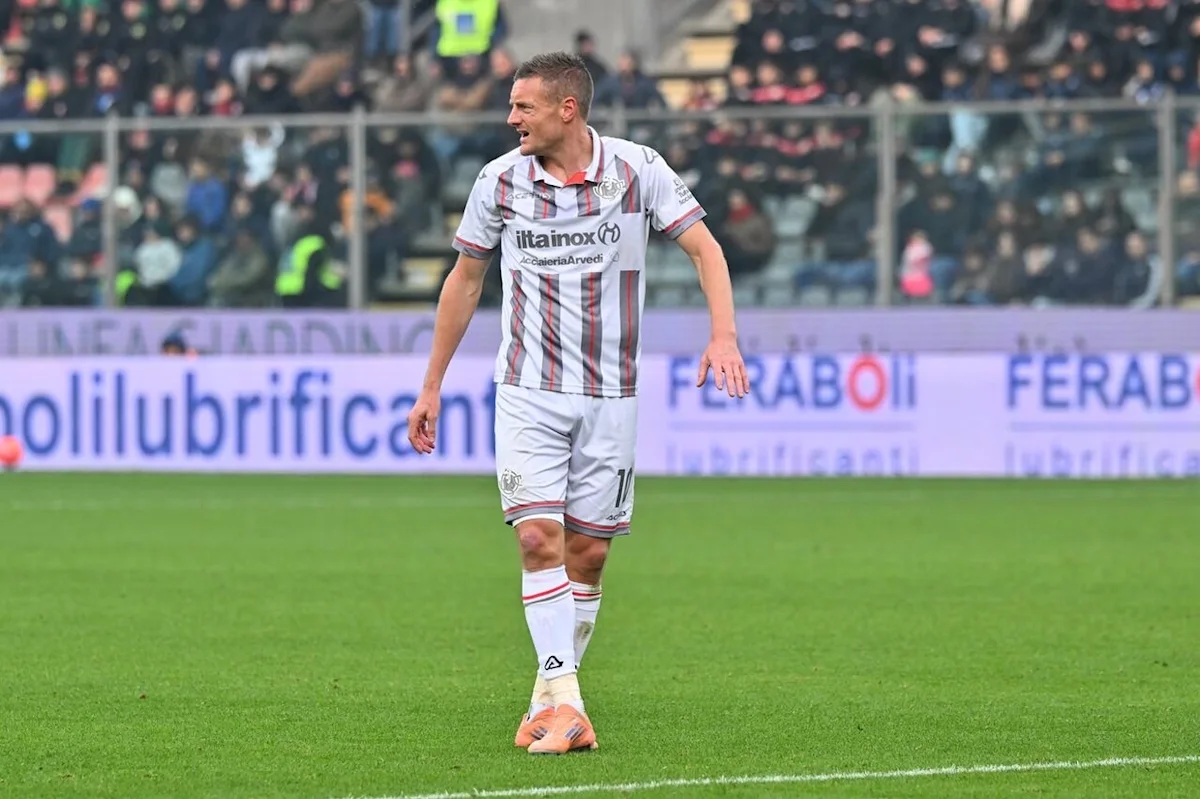 Footballer in a striped Cremonese jersey walks across the pitch during a match.